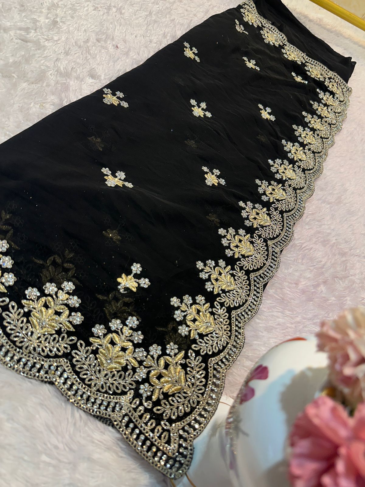 Black fabric with gold embroidery on a light pink surface
